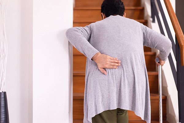 old lady walking up stairs with back pain